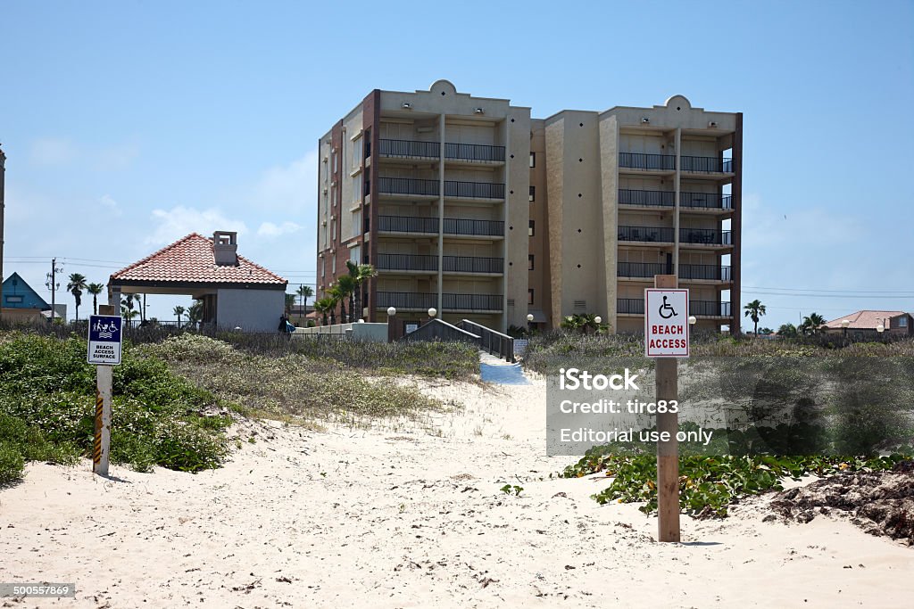 Beach walkway and condos at Port Isabel, Texas Port Isabel, TX, USA - May 21, 2014: Beach walkway entrance and condos at Port Isabel, Texas. Information signs are on posts in the sand Advice Stock Photo
