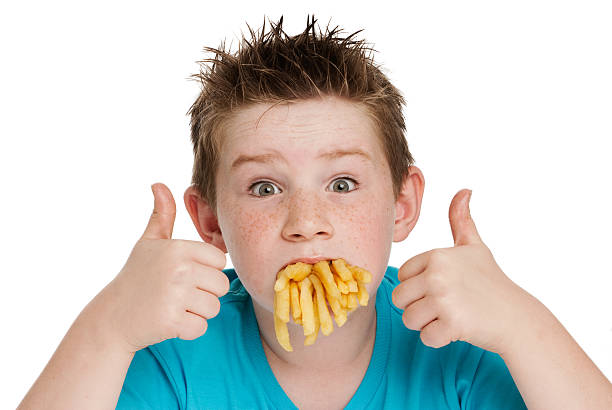 Young boy with a mouth full of chips fries. Isolated on white background.