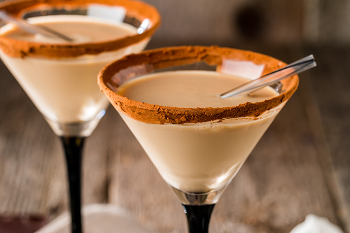 Irish cream liqueur in a glass with   cinnamon on wooden background
