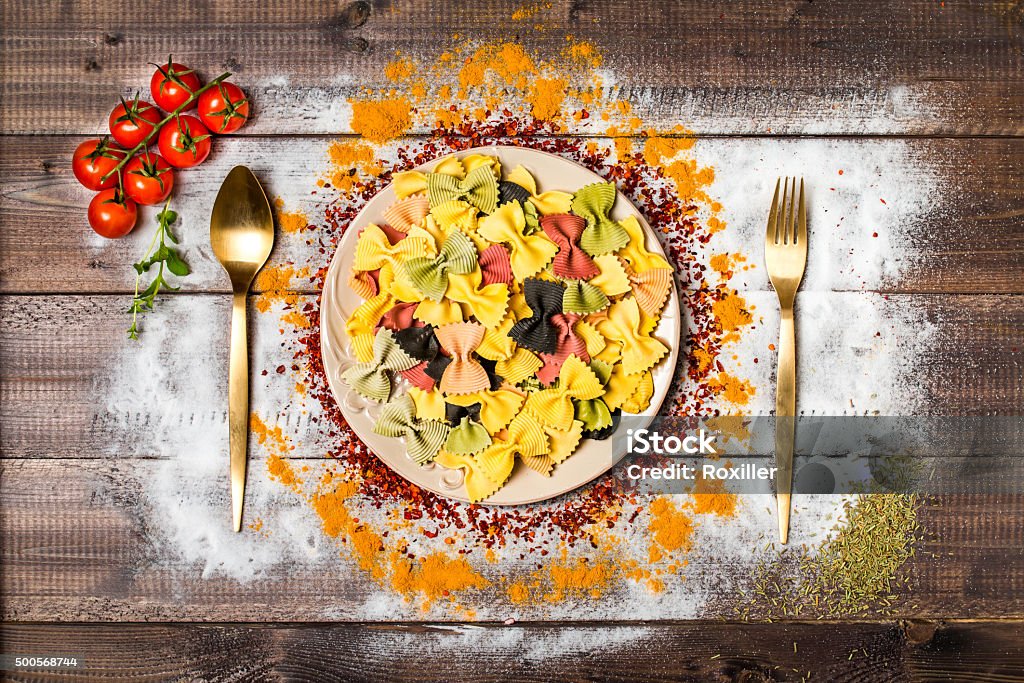 Spices on wooden table with cutlery silhouette colorful spices and farfalle on wooden table, top view 2015 Stock Photo