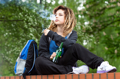 Rude girl smoking marijuana and drinking beer out of school