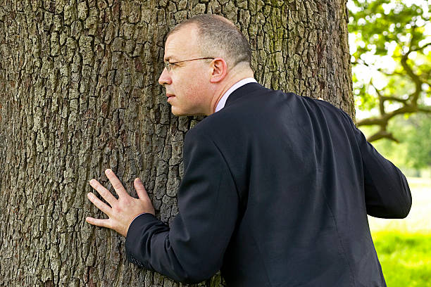 business man hugging a tree and listening stock photo