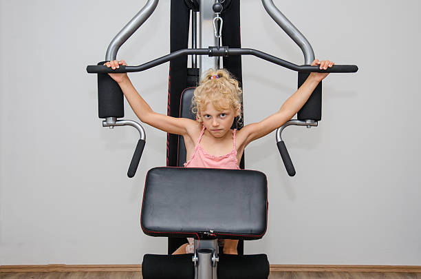 adorable little blond girl working out in the equipment in the gym