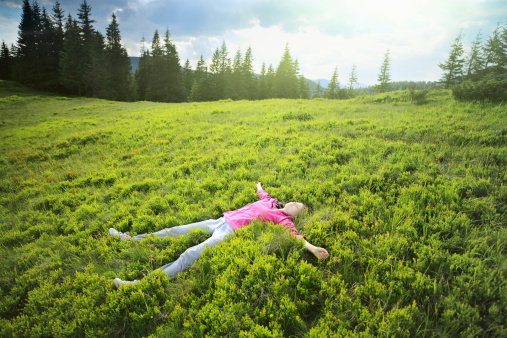 Woman lying on Grass on Mountain Side.