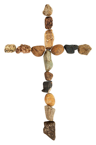 wooden cristian cross lying between littles stones on the ground
