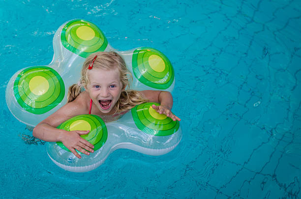 baby girl swims in the pool with an inflatable yellow circle in summer and shows the class, the concept of travel and recreation