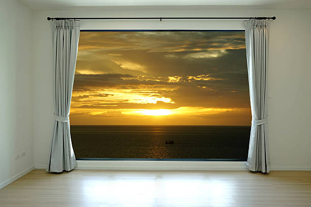 istock Empty room and curtain open to sunset at sea 500578475