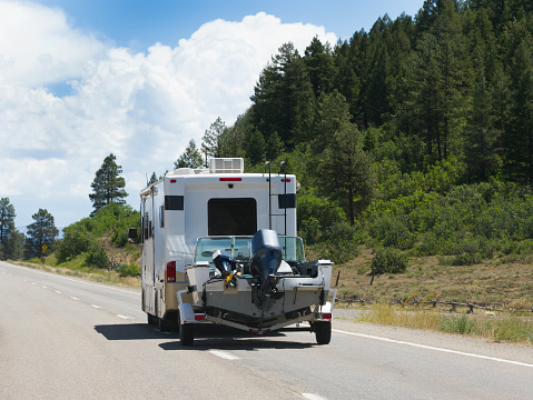 An RV pulling a boat on a scenic road in Colorado.