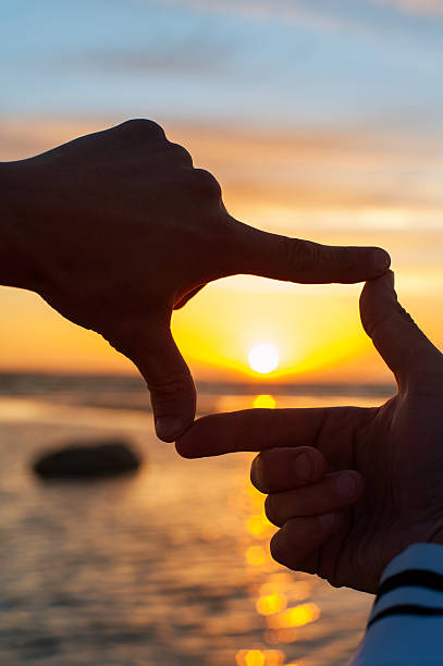 Finger frame-  imitation of capturing rays of sunset sunlight