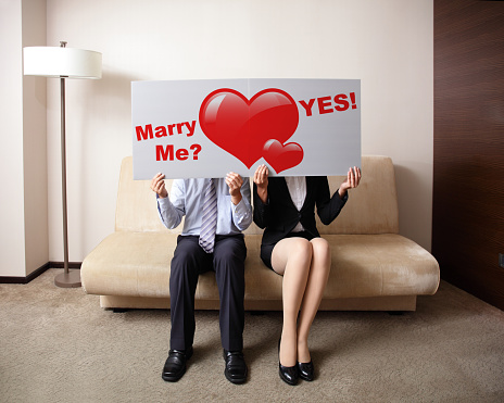 Happy young couple holding billboard sign with love heart, concept for marriage