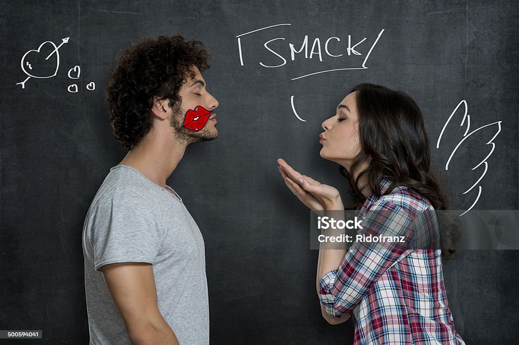 Woman Giving Flying Kiss To Man Woman Giving Flying Kiss To Her Boyfriend With Lip Sign On Cheek Over Gray Background Blowing a Kiss Stock Photo