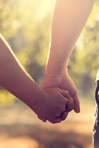 istock Young couple holding hands in park 500594304