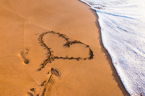 heart drawn in the sand by the sea