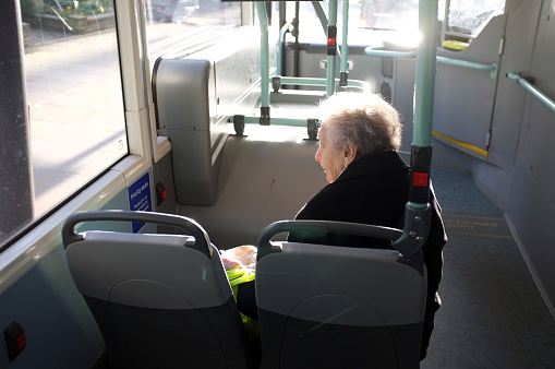 London, England - February 28, 2014: Senior citizen sits in the front seat and travels alone on a London bus