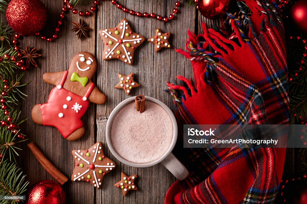 Cup of hot chocolate with gingerbread man, stars cookies and Cup of hot chocolate with gingerbread man, stars cookies and warm scarf composition in fir tree decorations frame on vintage wooden table background. Homemade traditional dessert recipe 2015 Stock Photo