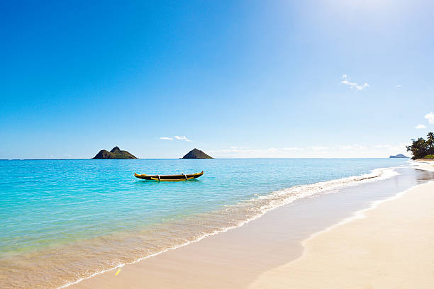 Outrigger Canoe on Lanikai Beach of Oahu Hawaii An outrigger canoe floating in aqua blue sea off of Lanikai beach on the southeast side of Oahu Hawaii with the Moku Iki island in the background. The idyllic Lanikai beach with its white sand and aqua blue water, a popular tourist destination of the island of Oahu in Hawaii. Photographed in horizontal format with copy space. oahu photos stock pictures, royalty-free photos & images