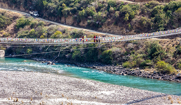 Bhutans longest suspension bridge Not far from the majestic dzong of Punakha,  is Bhutans longest suspension bridge. This type of bridge can be found everywhere in Bhutan. Dzongs are fortress like buildings which house a monastery and administrative offices. (unrecognizable people) monastery religion spirituality river stock pictures, royalty-free photos & images