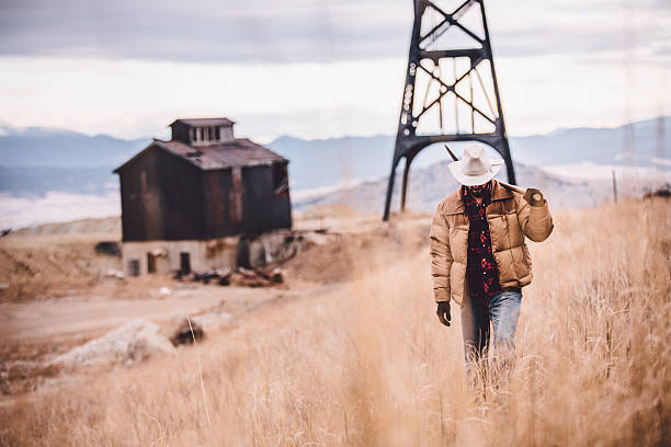 istock Western man with pickaxe ovrer shoulder walking through field 500611859