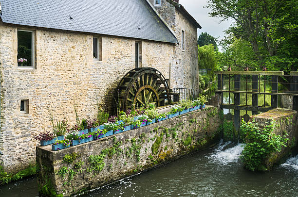 A wooden water wheel turns in the sluceway of an old  stone mill in Bayeux, France