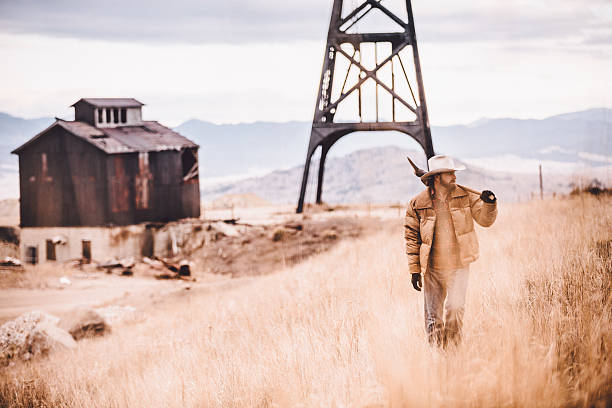 istock Rugged man carrying pickaxe over shoulder walking through western field 500613171