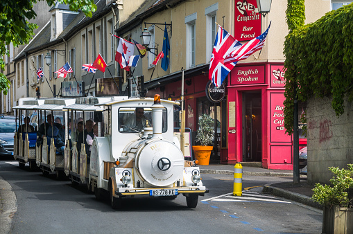 Bayeux, France- May 28, 2014: A group of tourists take in the sights and sounds of the village of Bayeux, France as they ride the electric powered tram