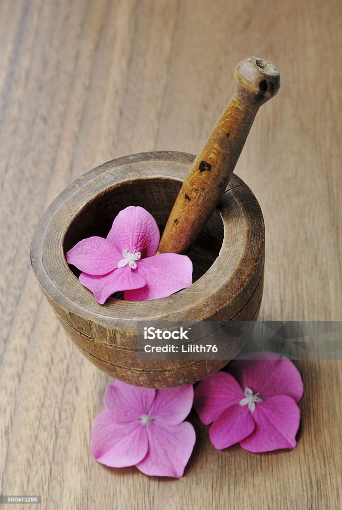 Flowers in a wooden pestle for aromatherapy and spa Flowers in a wooden pestle for aromatherapy and spa on a wooden background Backgrounds Stock Photo