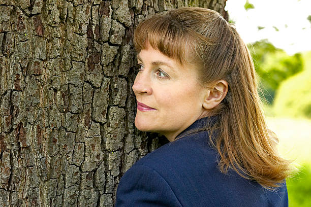 business woman hugging a tree and listening stock photo