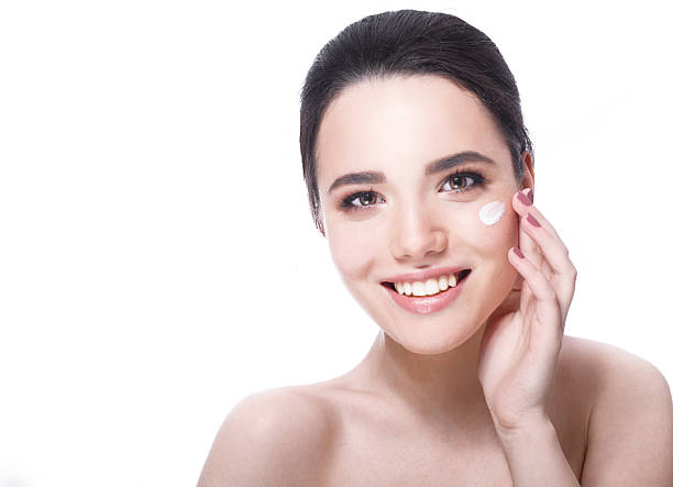 istock Smilling young woman applying moisturizer cream 500617922