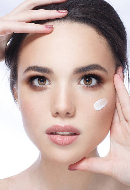 istock young woman applying moisturizer cream 500618136