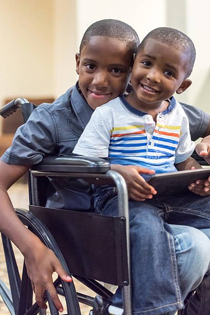behindertengerechte kind spielt mit seinem kleinen bruder - african ethnicity brother ethnic little boys stock-fotos und bilder