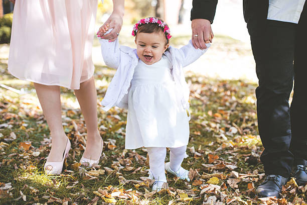 bambina fare i primi passi nel parco con i genitori - baby first steps autumn child foto e immagini stock