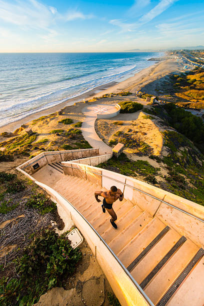 Muscular Man Running Up And Down The Stairs Muscular Man Running Up And Down The Stairs At The Ocean outdoor staircase stock pictures, royalty-free photos & images