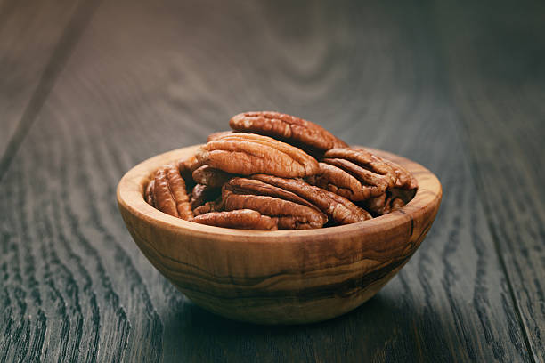 istock pecan nuts in olive wood bowl on oak table 500647158
