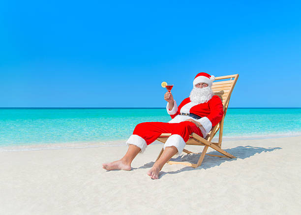 christmas santa claus com cocktail na cadeira de recosto na praia - christmas beach sun tropical climate imagens e fotografias de stock