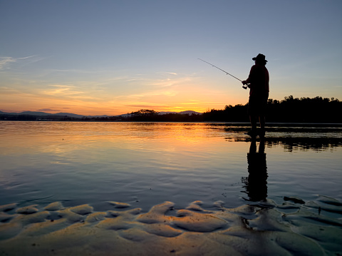 man fishing at sunset in bate mans bay