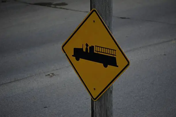 An upper view of a firetruck crossing sign on a busy street.