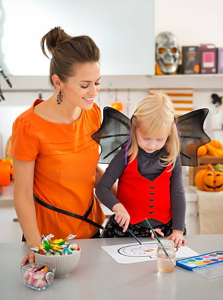 istock Mother with halloween dressed blond girl drawing Jack-O-Lantern 500664794