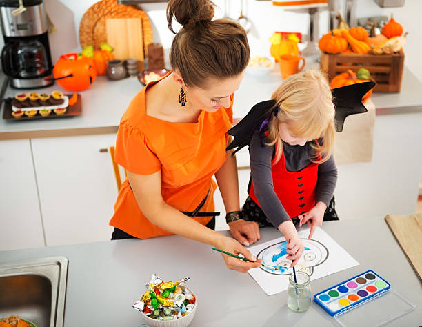 istock Halloween dressed girl with mother drawing Jack-O-Lantern 500664834