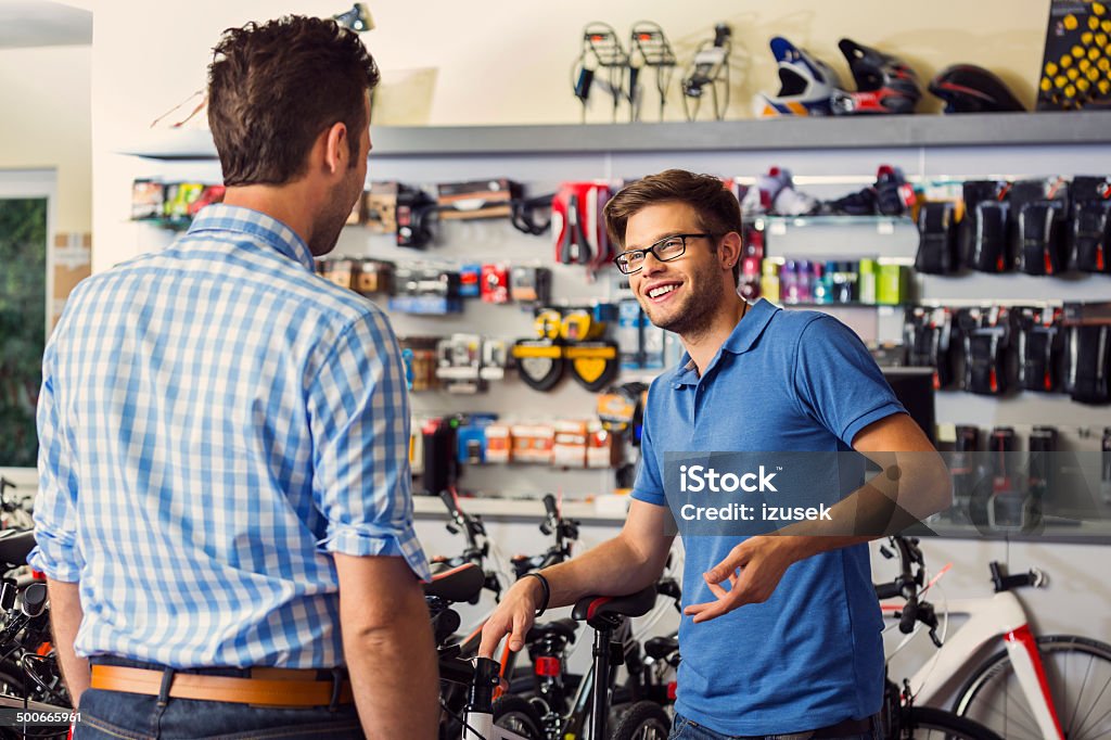 Man buying bicycle Man buying a bicycle in bike store, talking with shop assistant. Advice Stock Photo