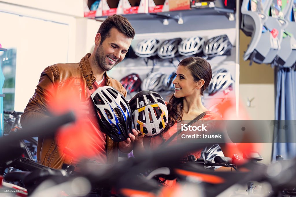 Couple bying bike helmets Cheerful couple watching a helmets in a bike store. Buying Stock Photo