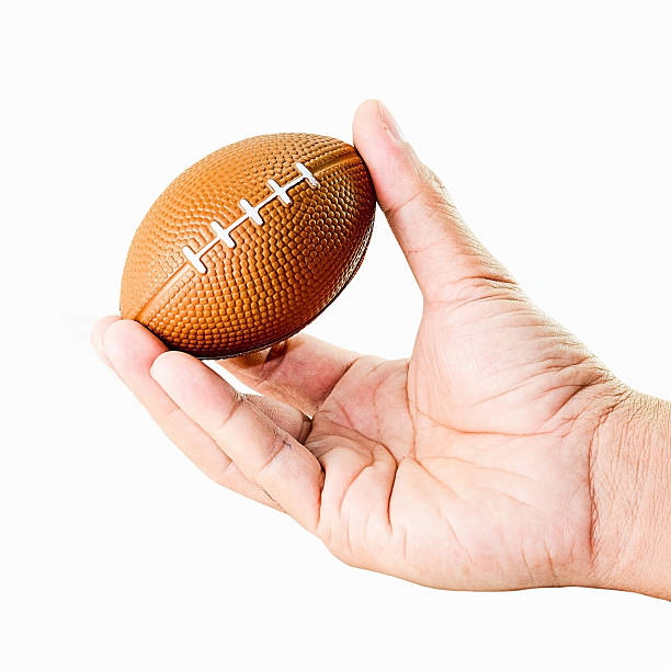 istock hand holding miniaturized rubber rugby ball over white background 500666306