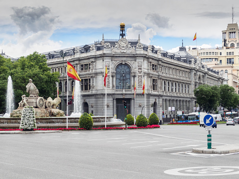 MADRID, SPAIN - JUNE 24, 2014: View of the facade of the Bank of Spain between trees and traffic in the square of Goddess Cybele.
