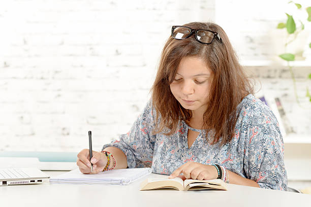istock student girl, with eyeglasses, does homework 500667680