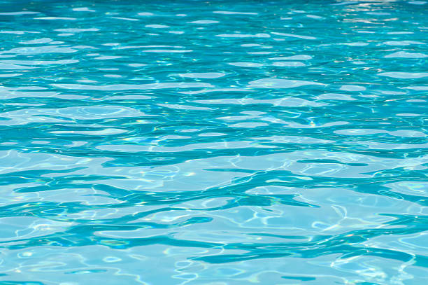 resplandeciente azul piscina superficie en un día soleado - superficie del agua fotografías e imágenes de stock