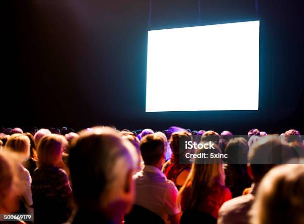 Audiencia Ve Una Pantalla En Blanco Brillante Foto de stock y más banco de imágenes de Sala de cine - Sala de cine, Pantalla de proyección, Dispositivo de pantalla