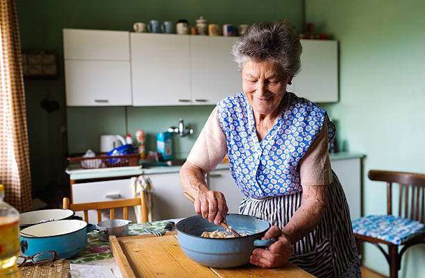 femme âgée faire cuire au four - cuisiner photos et images de collection