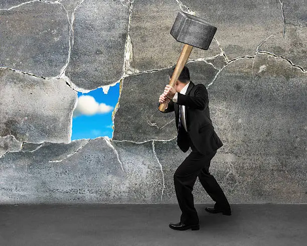 businessman destructing the wall with a large hammer