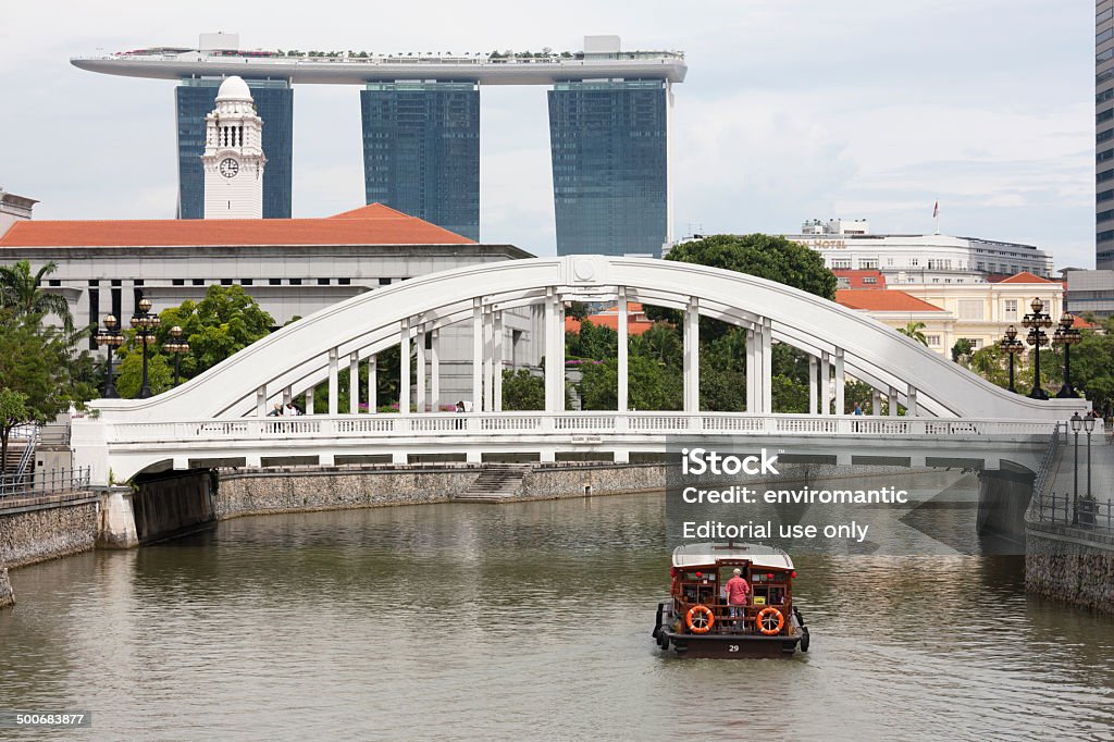City of diverse architectural styles, Singapore, Singapore, Singapore - October 6, 2010: A pleasure boat with tourist passengers passes under the famous white Elgin Bridge on the Singapore River, whilst the tourists enjoy views of Singapore's many different architectural styles, historical to present, such as the clock tower of Victoria Memorial Hall to the modern Marina Bay Sands Resort in the background. Architecture Stock Photo