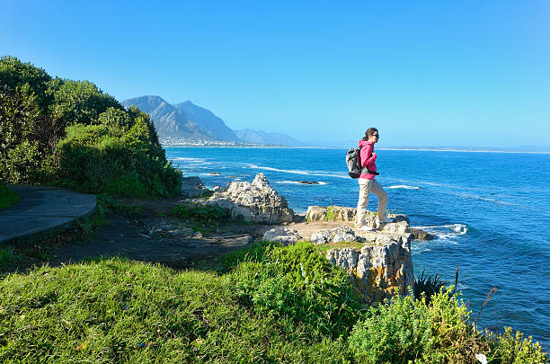 Woman hiking and looking at beautiful ocean view Woman looking at beautiful ocean view in Hermanus, vacation and travel in South Africa hermanus stock pictures, royalty-free photos & images