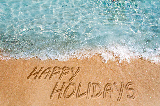 Happy holidays sign on the beach sand